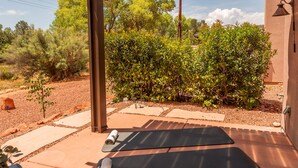 An outdoor patio with two yoga mats, a small table with a plant, and a wall-mounted light fixture. - Private Home with Courtyard, Walk to Trails & Dining, Pets Welcome! (Sedona)