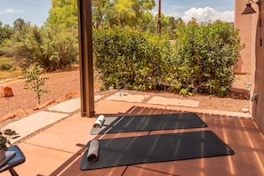 En uteplats med två yogamattor, ett litet bord med en växt och en väggmonterad lampa.