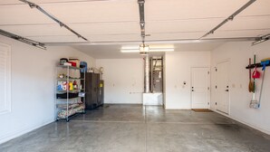 A clean, empty garage with a concrete floor, metal shelving unit, and a door leading to another room. - Private Home with Courtyard, Walk to Trails & Dining, Pets Welcome! (Sedona)