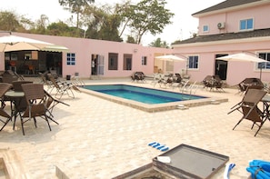 Una piscina al aire libre, sombrillas, sillones reclinables de piscina