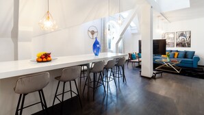 Eine moderne Küche mit weißer Arbeitsplatte, Barhocker und Pendelleuchten.