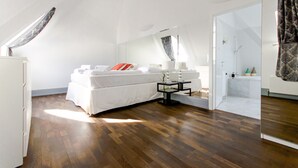Ein Schlafzimmer mit Bett, Nachttisch, Spiegel und begehbarem Kleiderschrank.