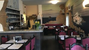 A restaurant interior with a bar area, seating, and a mural on the wall.