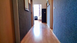 A long, narrow hallway with wooden flooring and walls painted in two different colors.