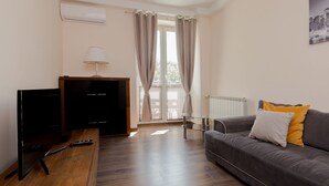 A room with a sofa, a TV, a lamp, and a window with curtains. - ShortStayPoland Staszica B76 (Warsaw)