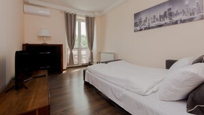 A bedroom with a bed, a desk with a computer, a lamp, and a window with curtains. - ShortStayPoland Staszica B76 (Warsaw)