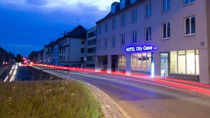 Een hotel met een moderne gevel, veel ramen en een opvallend neonbord.