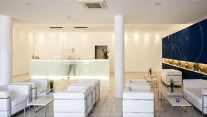 Een moderne hotellobby met een receptiebalie, zithoek en decoratieve wand.