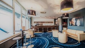 Een moderne loungeruimte met een bar, zitplaatsen en een kamerbreed tapijt.