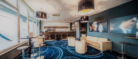 A modern lounge area with a bar, seating, and a patterned carpet.