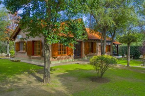 Una casa de ladrillo con contraventanas de madera, un porche cubierto y un césped bien cuidado.