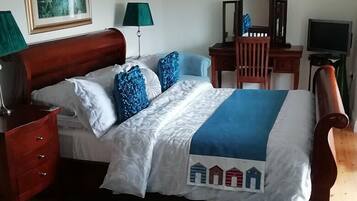 A neatly made bed with a blue and white bedspread, a wooden headboard, and a bedside table with a lamp.