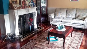 A living room with a fireplace, a sofa, a coffee table, and a rug. - Tig na Coille B&B Country House (Tullaroan)