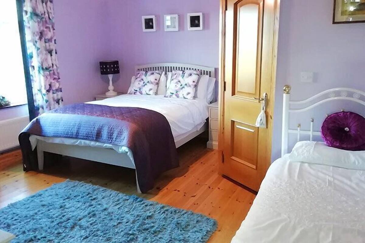 A bedroom with a bed, a nightstand, a dresser, and a door.