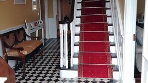 A staircase with red carpeted steps, a chandelier, and a checkered floor. - Tig na Coille B&B Country House (Tullaroan)