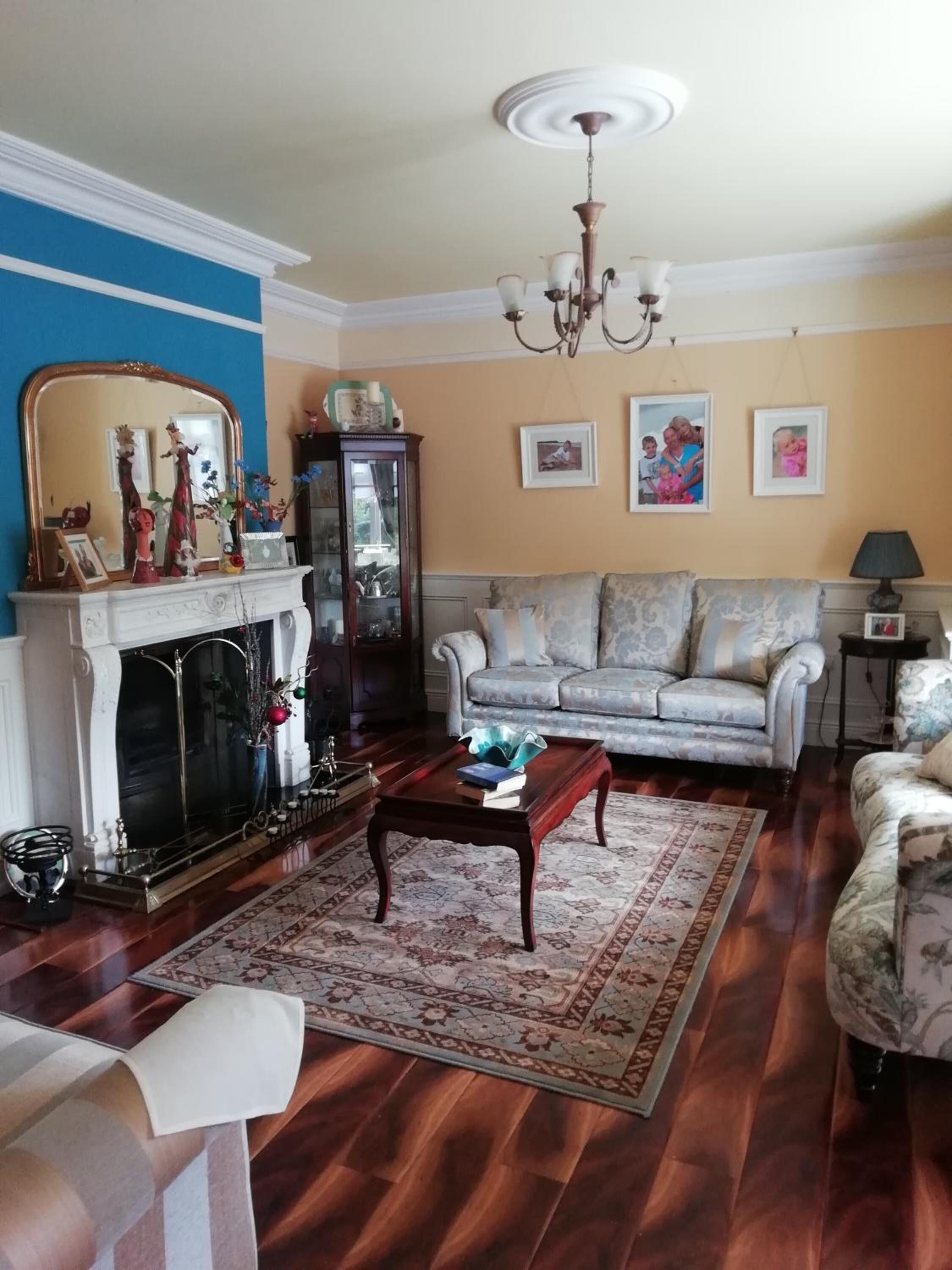 A living room with a fireplace, a sofa, a coffee table, and a chandelier.