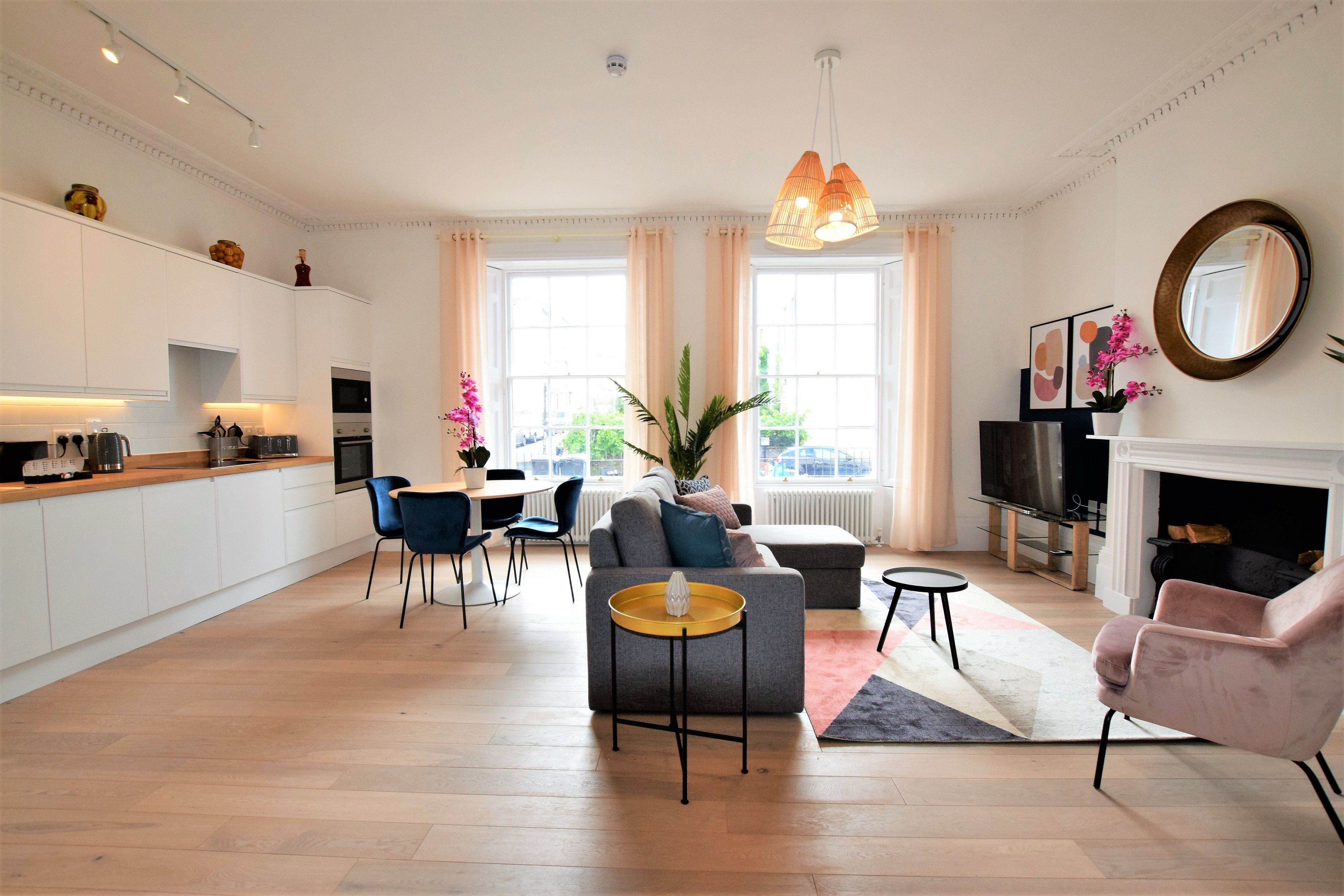 Ein modernes Wohnzimmer mit Sofa, Sesseln, einem Couchtisch und einem Kamin.
