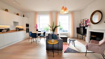 Ein modernes Wohnzimmer mit Sofa, Sesseln, einem Couchtisch und einem Kamin.