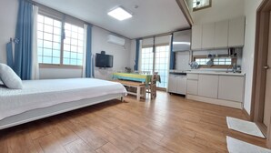 Een slaapkamer met een bed, een bureau en een kitchenette.