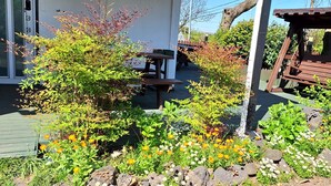 Een tuin met een houten bankje, een klein tafeltje en een houten schommel.