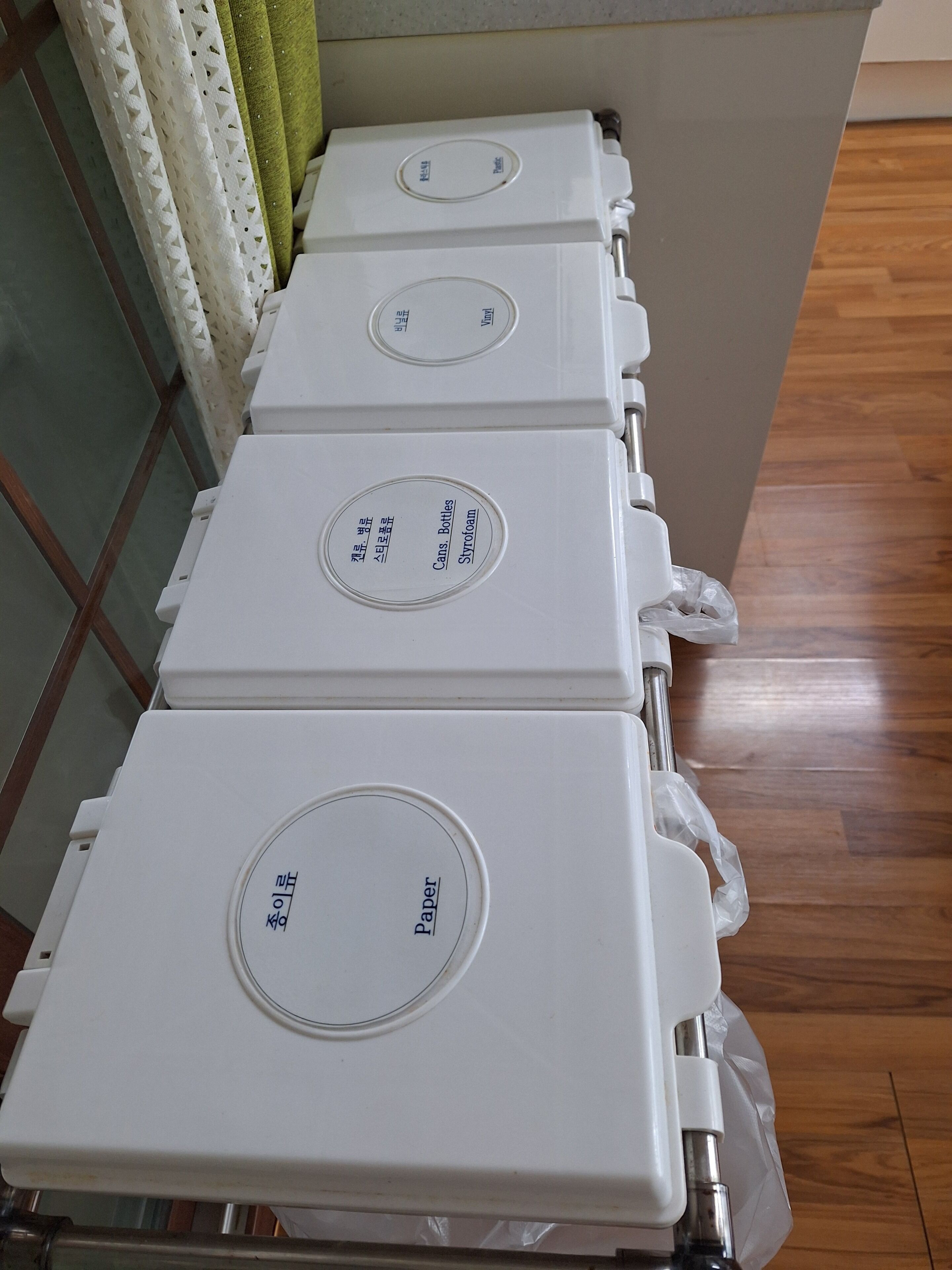 A row of white, rectangular storage units with labels indicating contents such as paper, styrofoam, and cans.