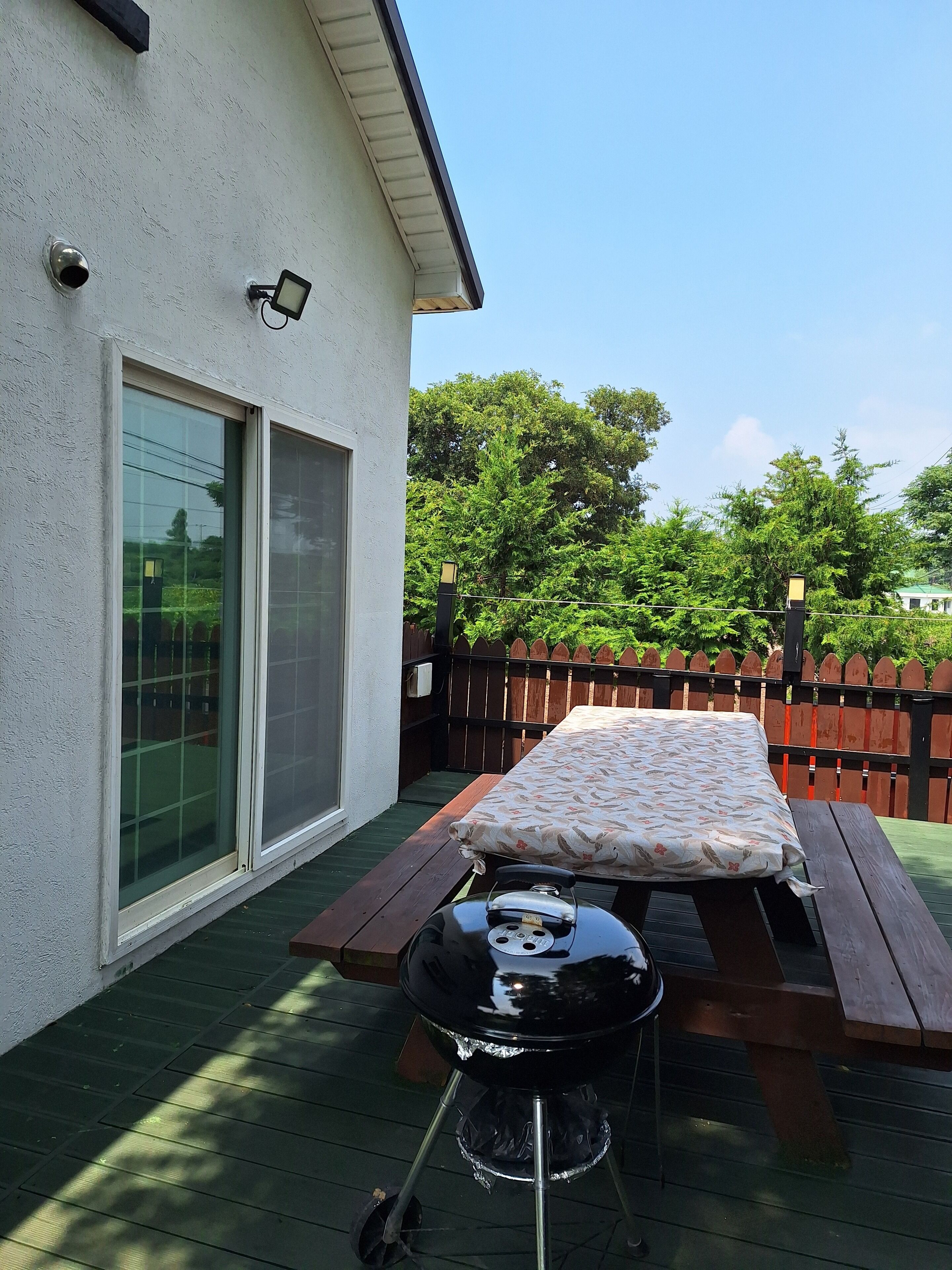 A patio with a barbecue grill, a picnic table, and a sliding glass door.