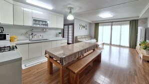 Een moderne keuken met witte kastjes, een eettafel met geruit tafelkleed en een houten bank.