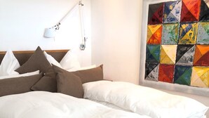A bed with white bedding, a wooden headboard, and a bedside table with a lamp. - Panorama52 (Remseck am Neckar)