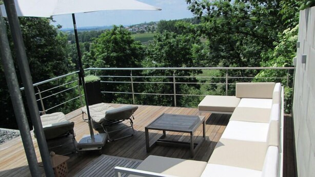 A deck with outdoor furniture, including a sofa and a table, surrounded by a metal railing. - Panorama52 (Remseck am Neckar)