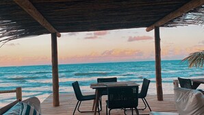 A wooden deck with lounge chairs and a table, overlooking the ocean at sunset. - Paru Boutique Hotel (Passo de Camaragibe)