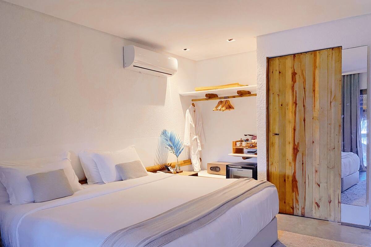 Une chambre moderne avec un grand lit, des tables de chevet, une armoire en bois et un petit bureau avec une chaise.