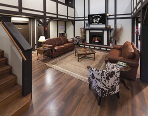 A cozy living room with a fireplace, leather sofas, a coffee table, and a patterned armchair. - Highland Lodge (Cleveland)