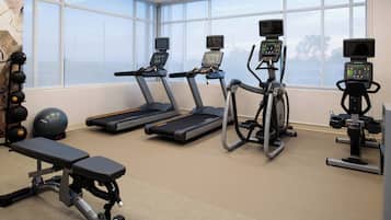 A gym with treadmills, elliptical machines, and a bench.