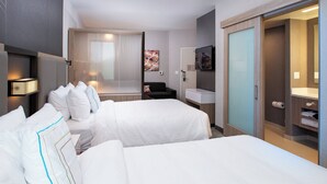 Een hotelkamer met twee bedden, een bureau, een stoel, een televisie, een spiegel en een kledingkast.