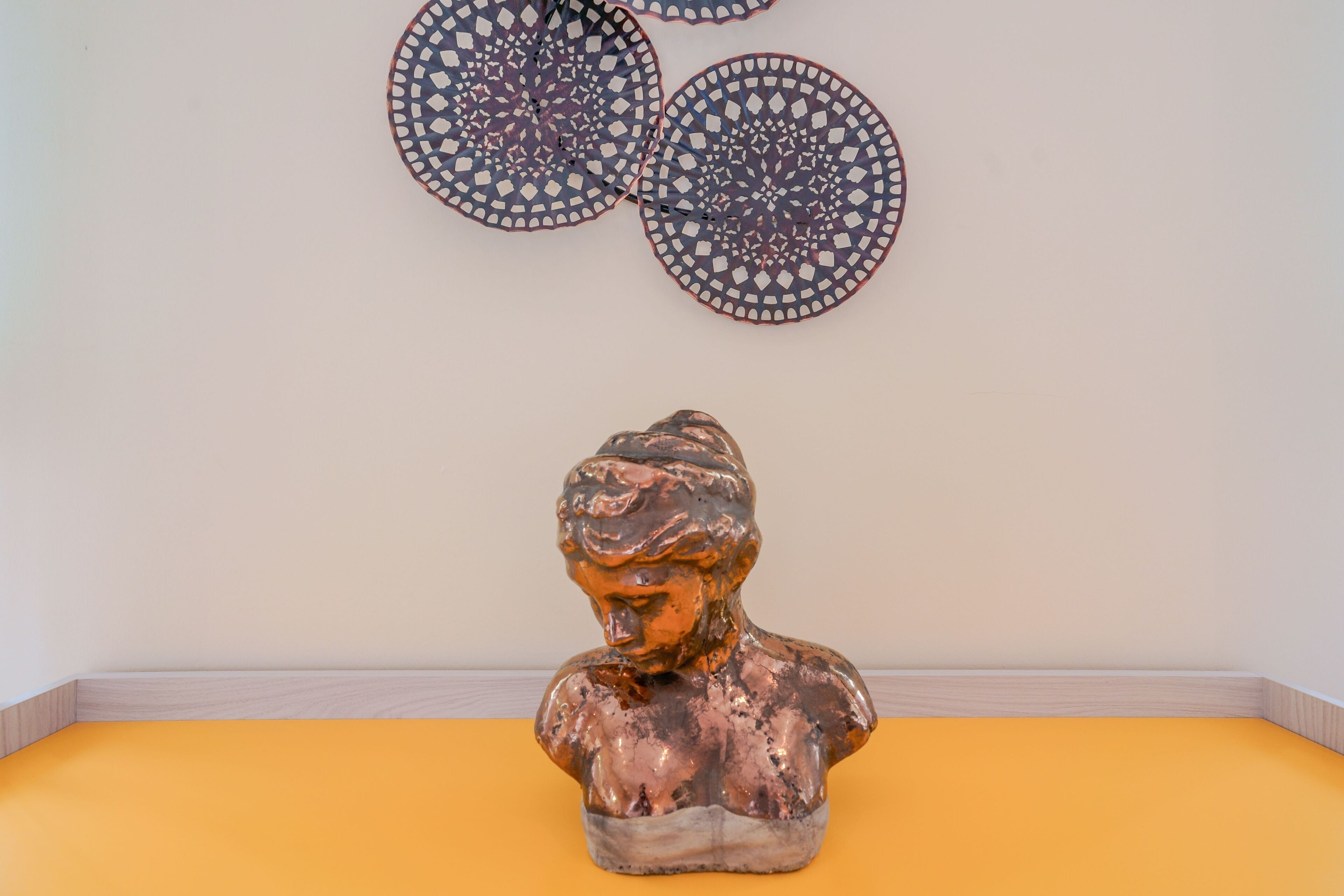 Un busto sobre una superficie amarilla con decoraciones de pared estampadas.