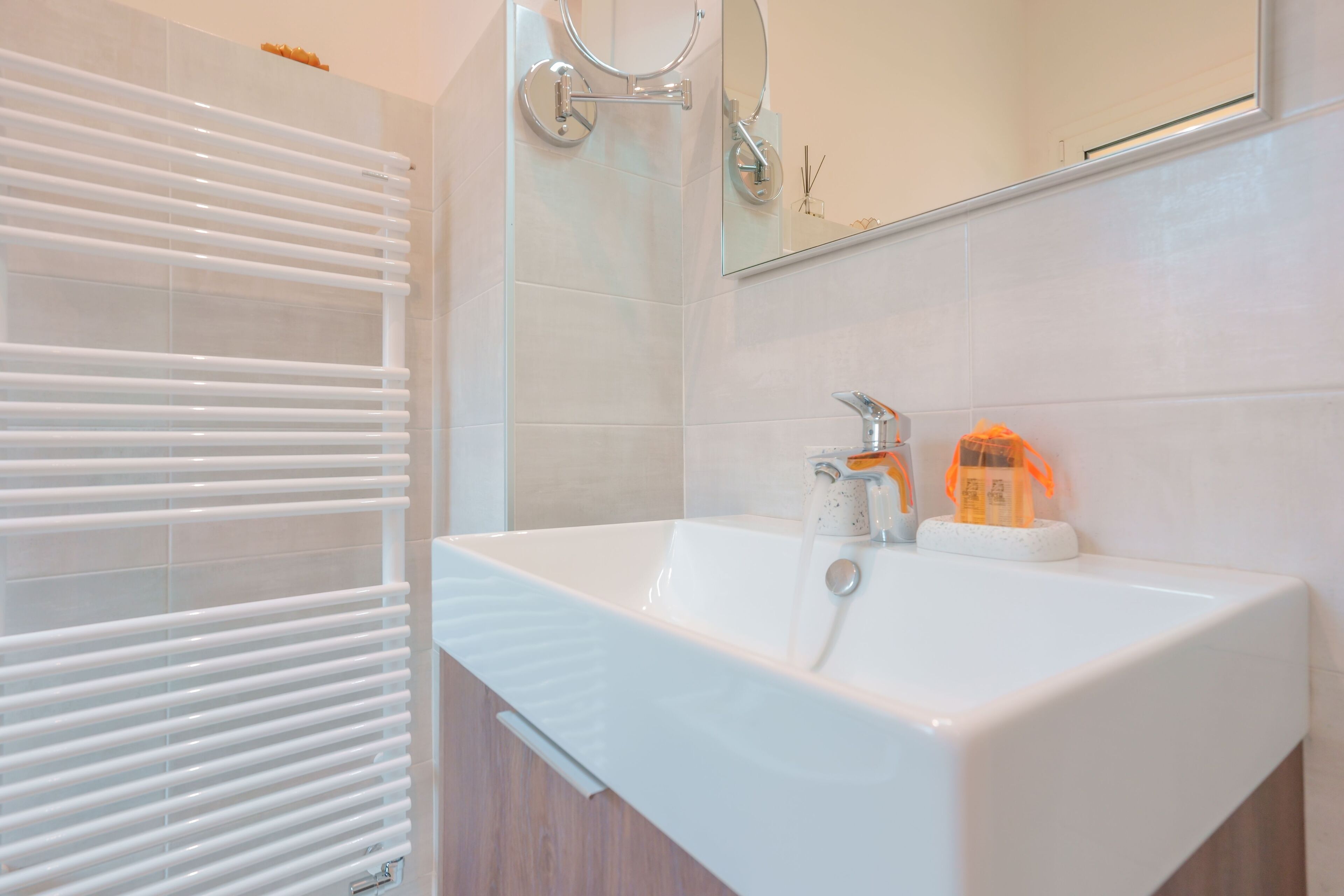 Une salle de bain moderne avec un lavabo blanc, un miroir et un porte-serviettes.