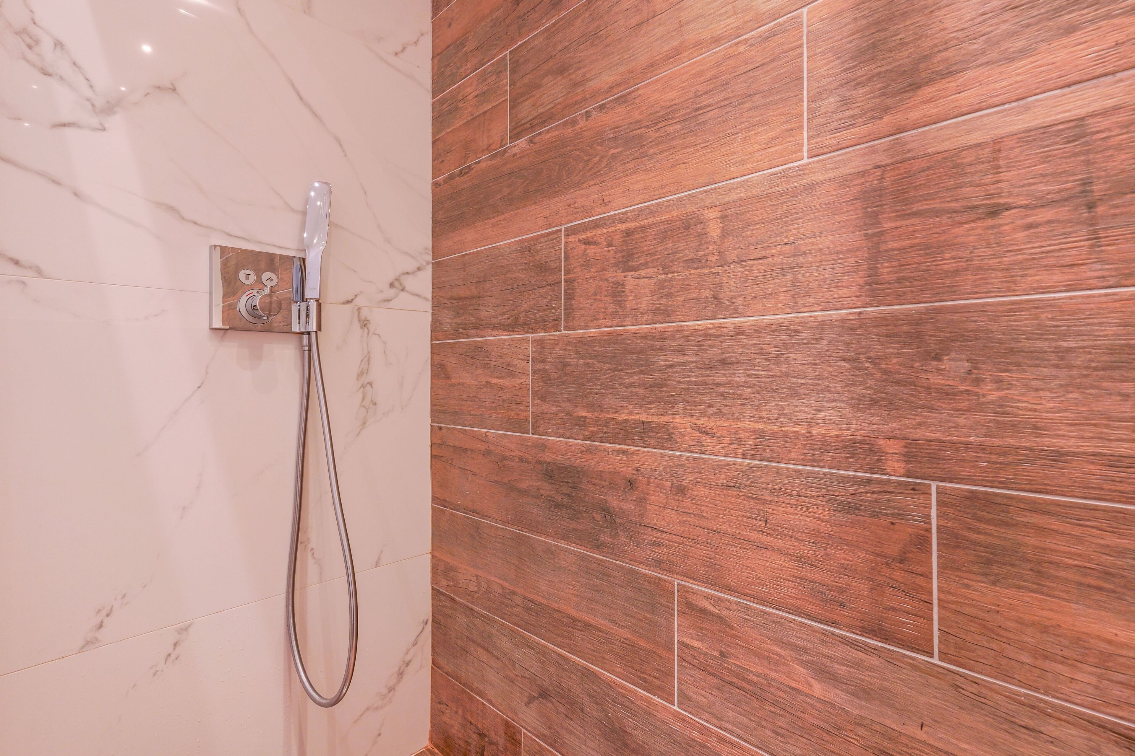 Eine Dusche mit Marmorwand und Holzboden.
