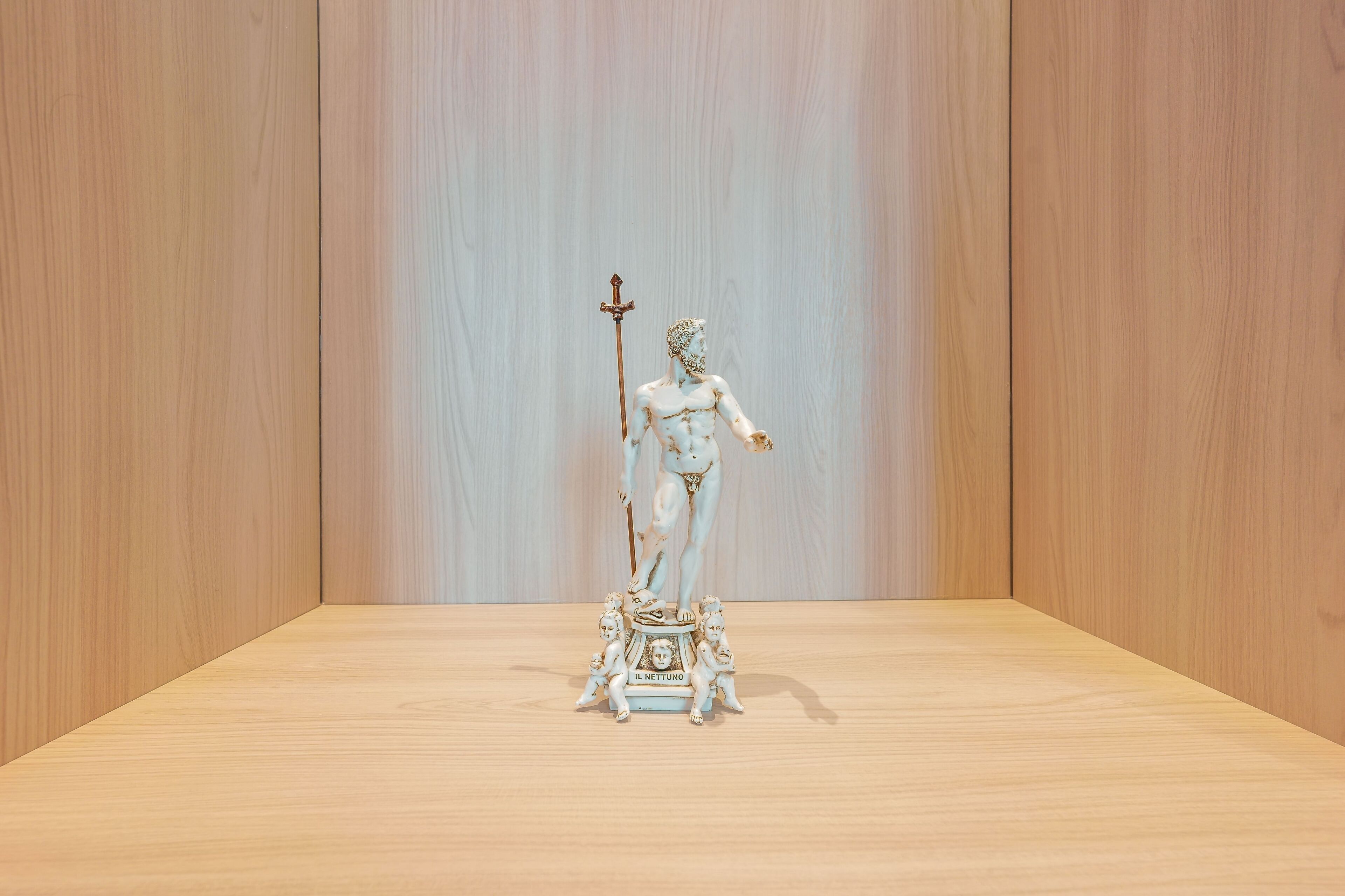 Una estatua de figura clásica sobre un pedestal en una habitación con paneles de madera.