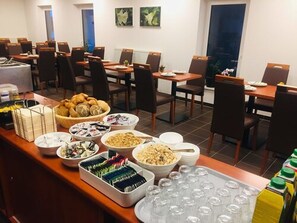 A buffet setup with various food items and beverages in a hotel dining area. - Hotel Mirabell (Erlangen)