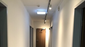 A narrow hallway with a blue carpet, white walls, and a wooden door at the end. - Hotel Mirabell (Erlangen)