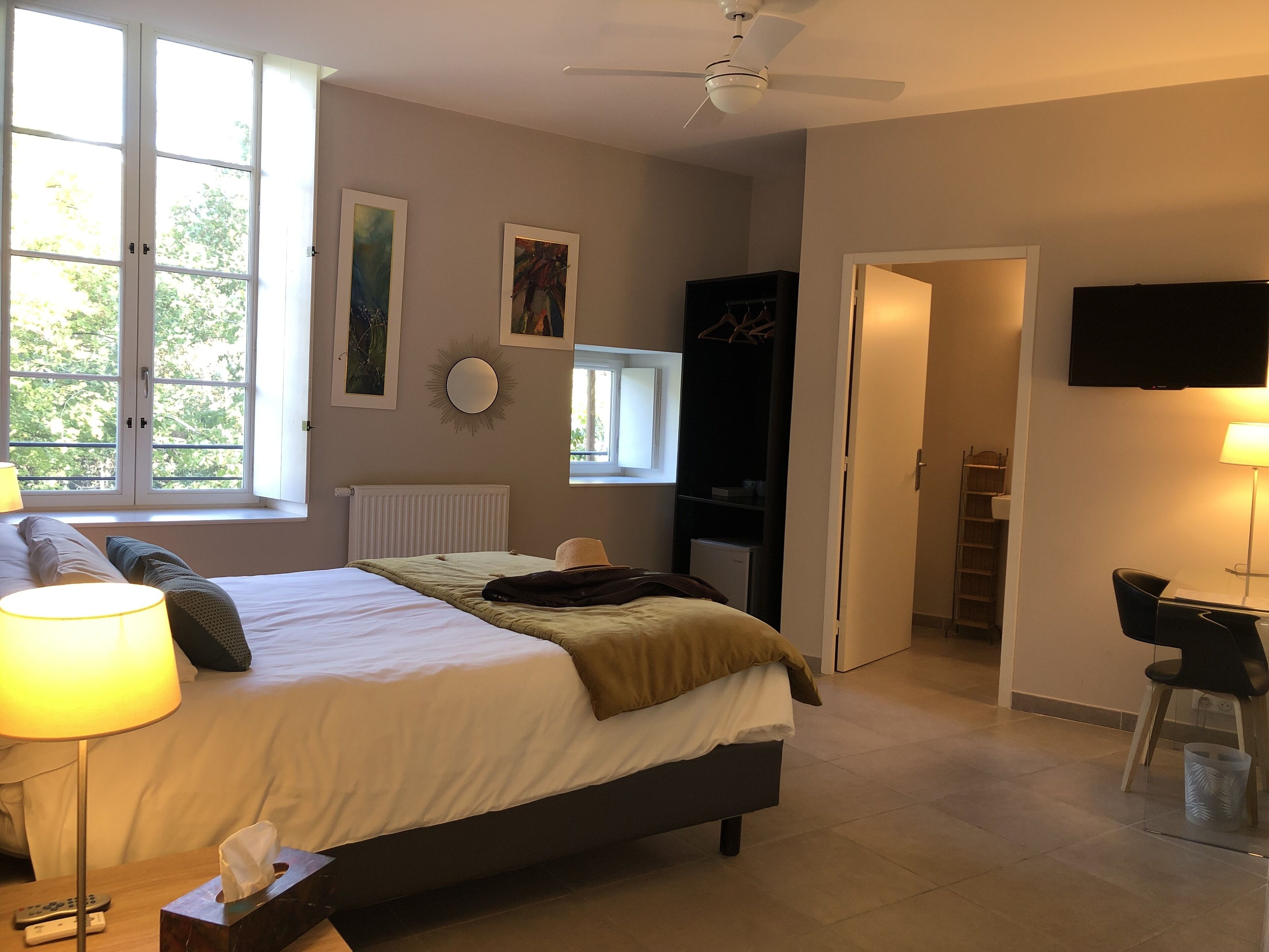 Un dormitorio con cama, lámparas de noche, televisor y escritorio con silla.