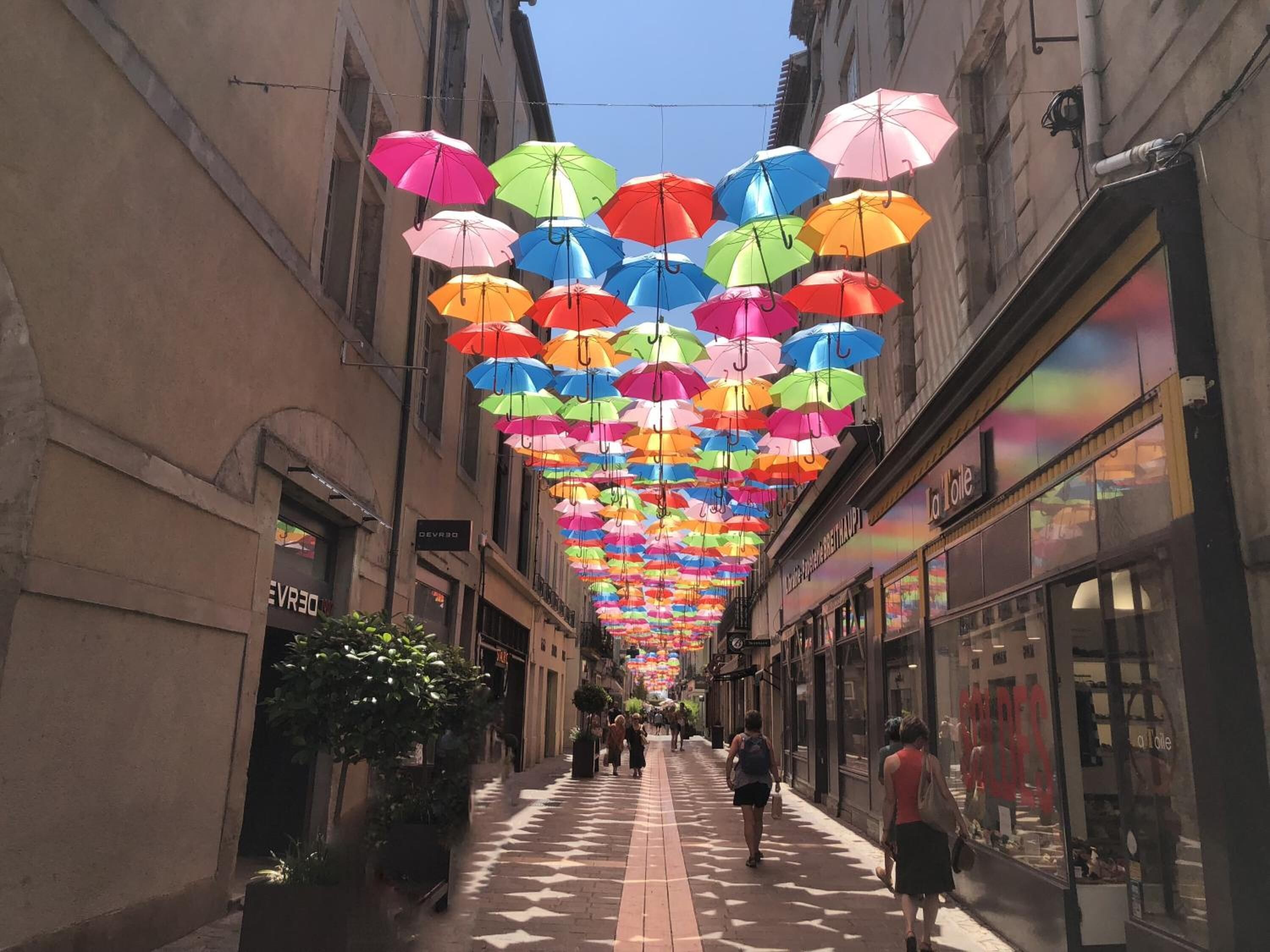 A street with colorful umbrellas hanging overhead.