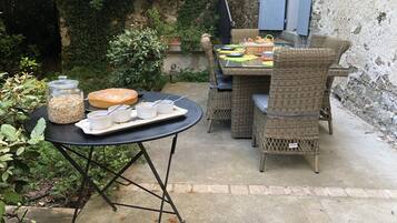 Una terrazza esterna con mobili in vimini, un tavolo con un vassoio di cibo e bevande, e un barattolo di avena.