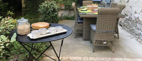 An outdoor patio with wicker furniture, a table with a tray of food and drinks, and a jar of oats.