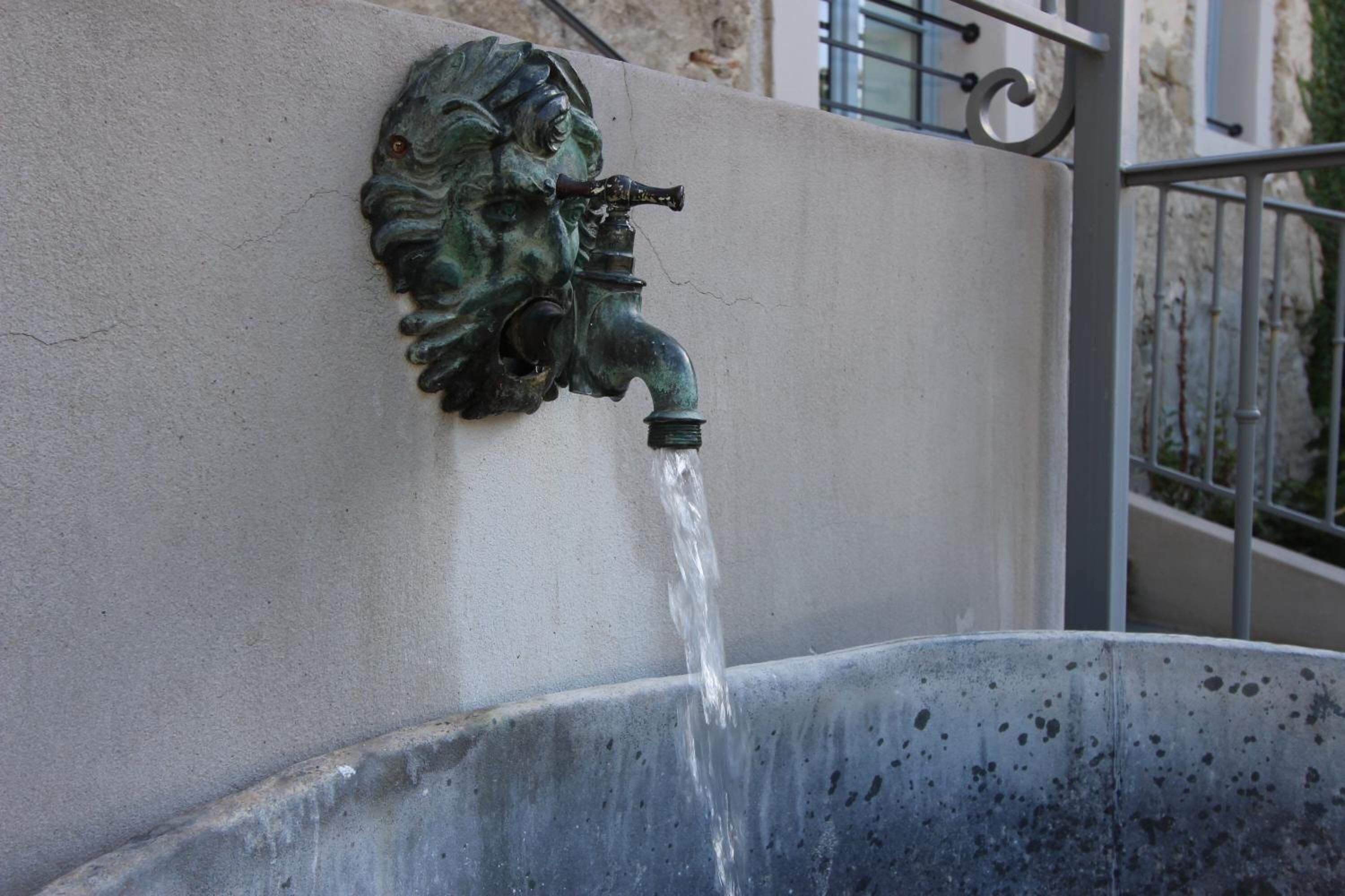Un caño metálico que vierte agua en una bacha de metal.