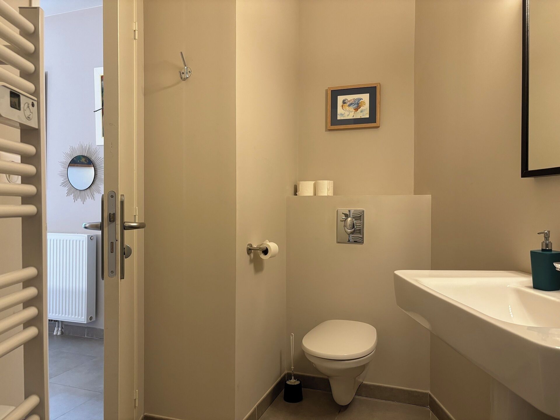 A bathroom with a toilet, sink, and a framed picture on the wall.