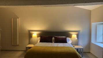 A hotel room with a bed, two bedside lamps, a nightstand, a window, and a mirror.