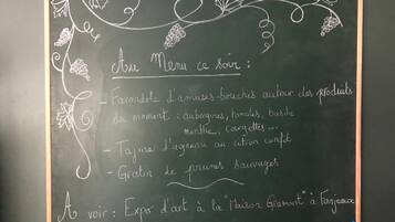 A chalkboard menu with a list of food items and a note about an art exhibition.