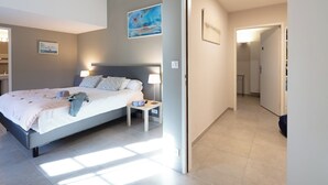 A modern bedroom with a bed, bedside tables, and a painting on the wall. - Le Grenier Occitan (Gramazie)