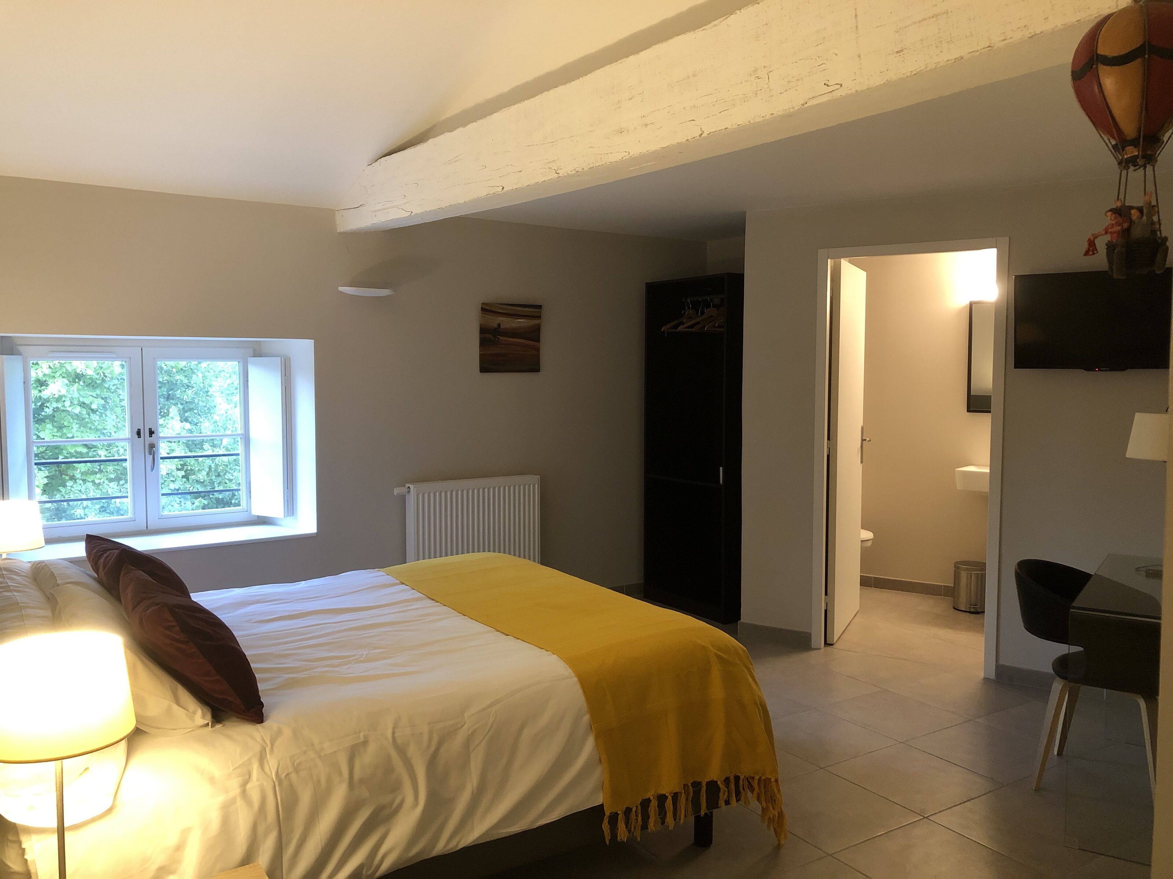 A bedroom with a bed, a window, a radiator, a wardrobe, and a television.